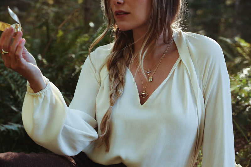 Model holding officially licensed Harry Potter Golden Snitch ring box and wearing Winged Key, Mirror of Erised, and Time Turner necklaces in 14k yellow gold. Also available in other precious metals.